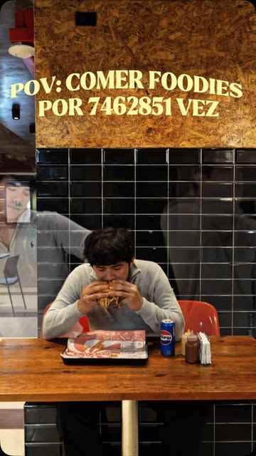 Cliente comiendo en la barra de Foodies bajo un letrero que dice POV: comer Foodies por 7462851 vez