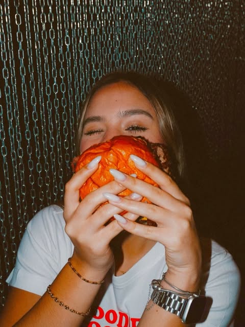 Una chica le da un mordisco grande a su hamburguesa